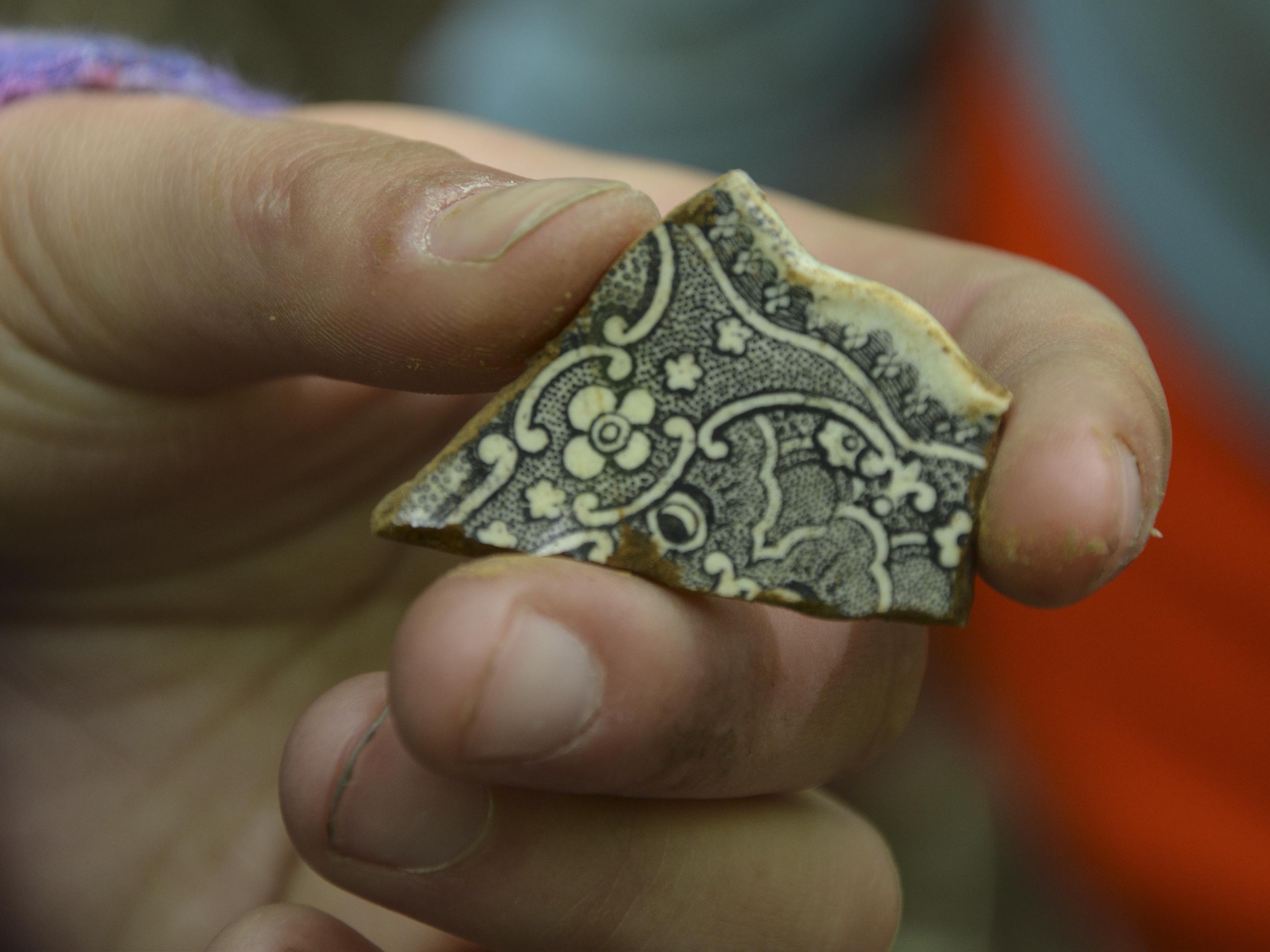 A fragment of a clay pot, intricately decorated with black line drawings.