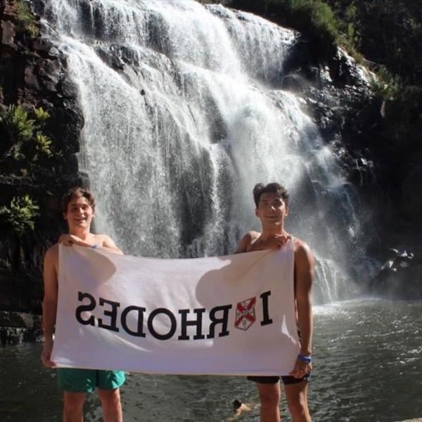 两个年轻人站在湍急的瀑布前，举着“我爱罗兹”的横幅.